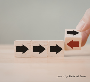 Three wood blocks lined up with black arrows on them, all facing the same direction. A fourth wood block at the end in someone's hand with a red arrow facing the opposite direction,