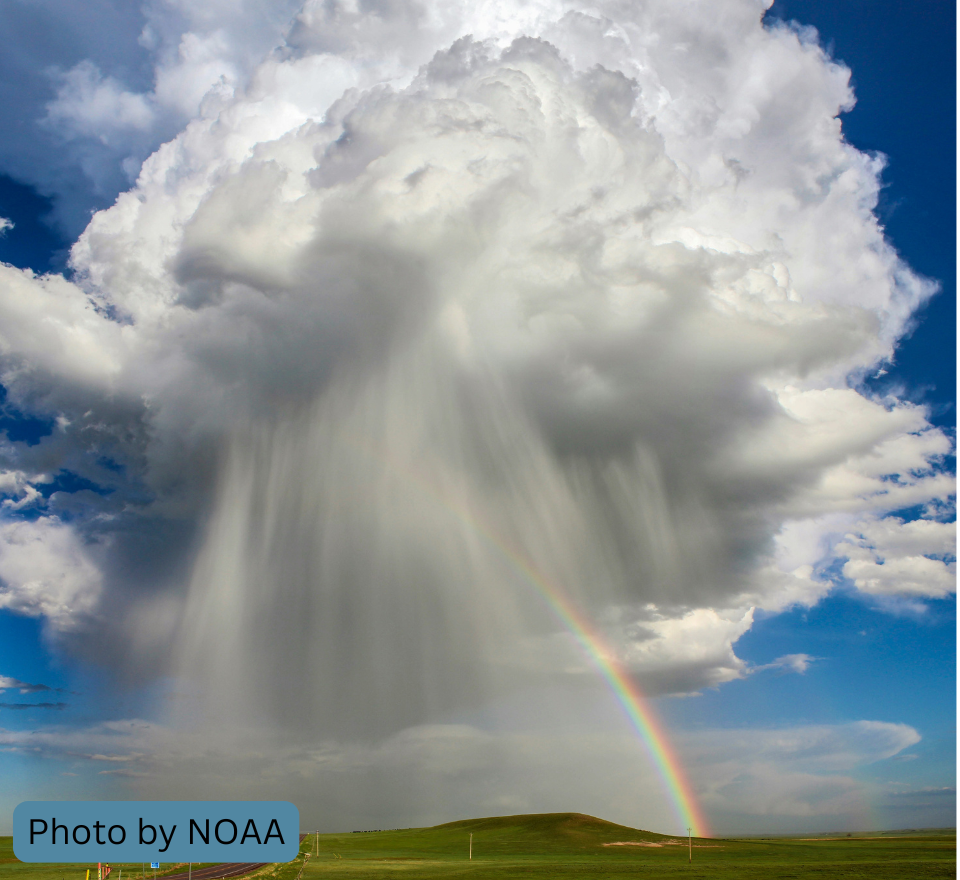 large cloud in the sky with rain pouring out of it and a rainbow off to the side.